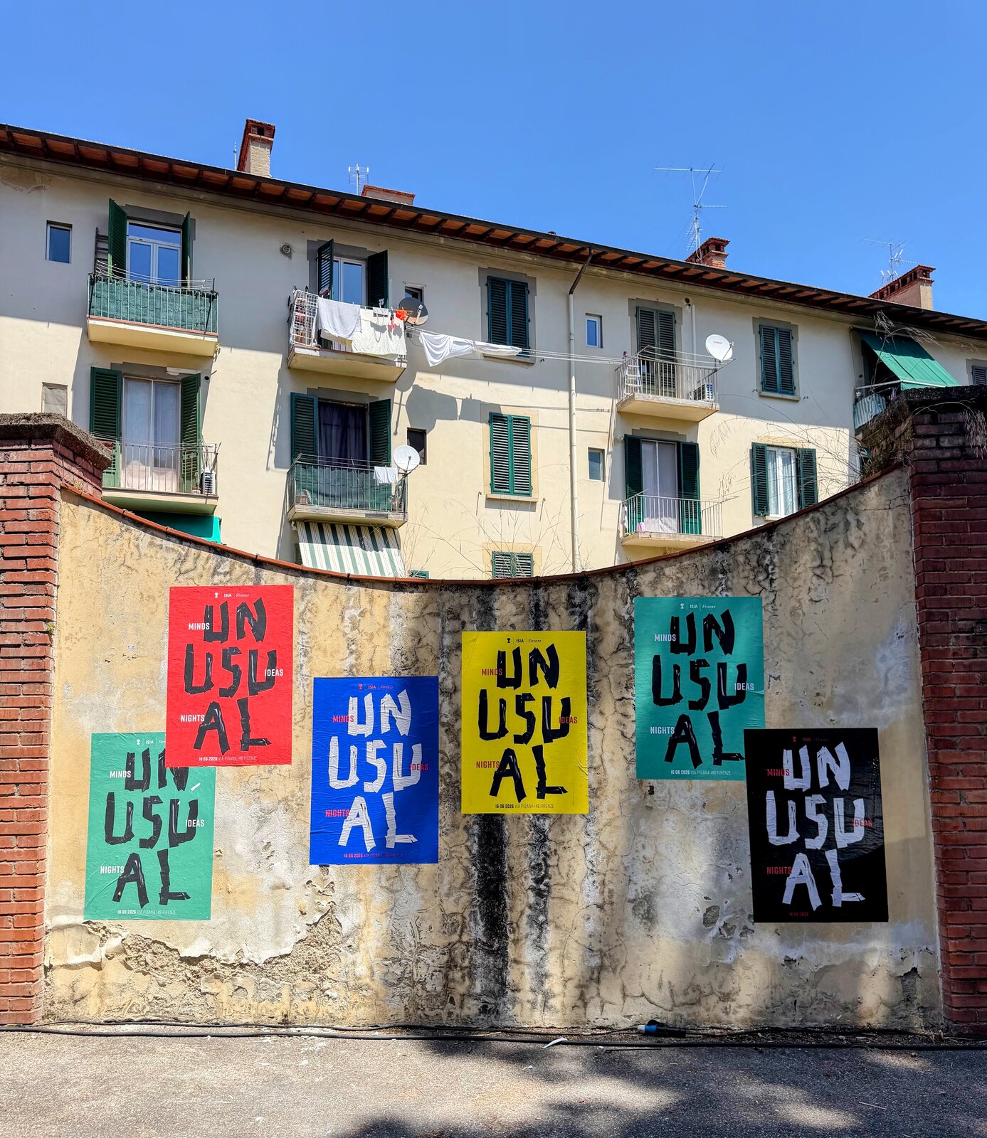 Colourful UNUSUAL Minds, Ideas, Nights posters pasted on a wall outside the ISIA Firenze venue